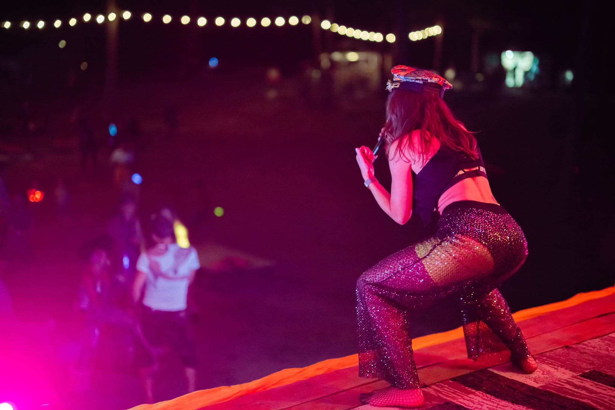 Lara Brightside performing under vivid pink stage lighting.
